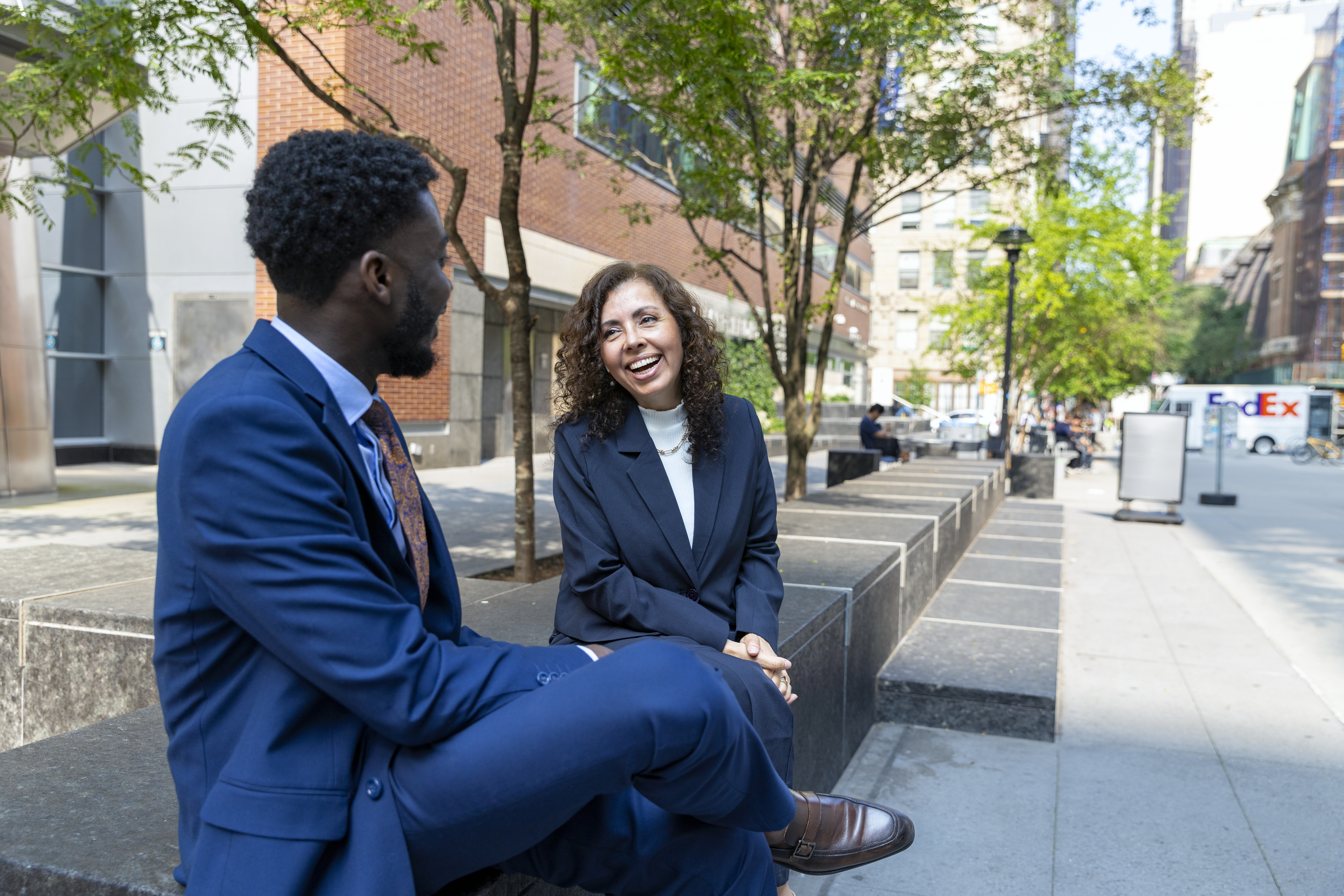 A man and women in suits are talking at the street