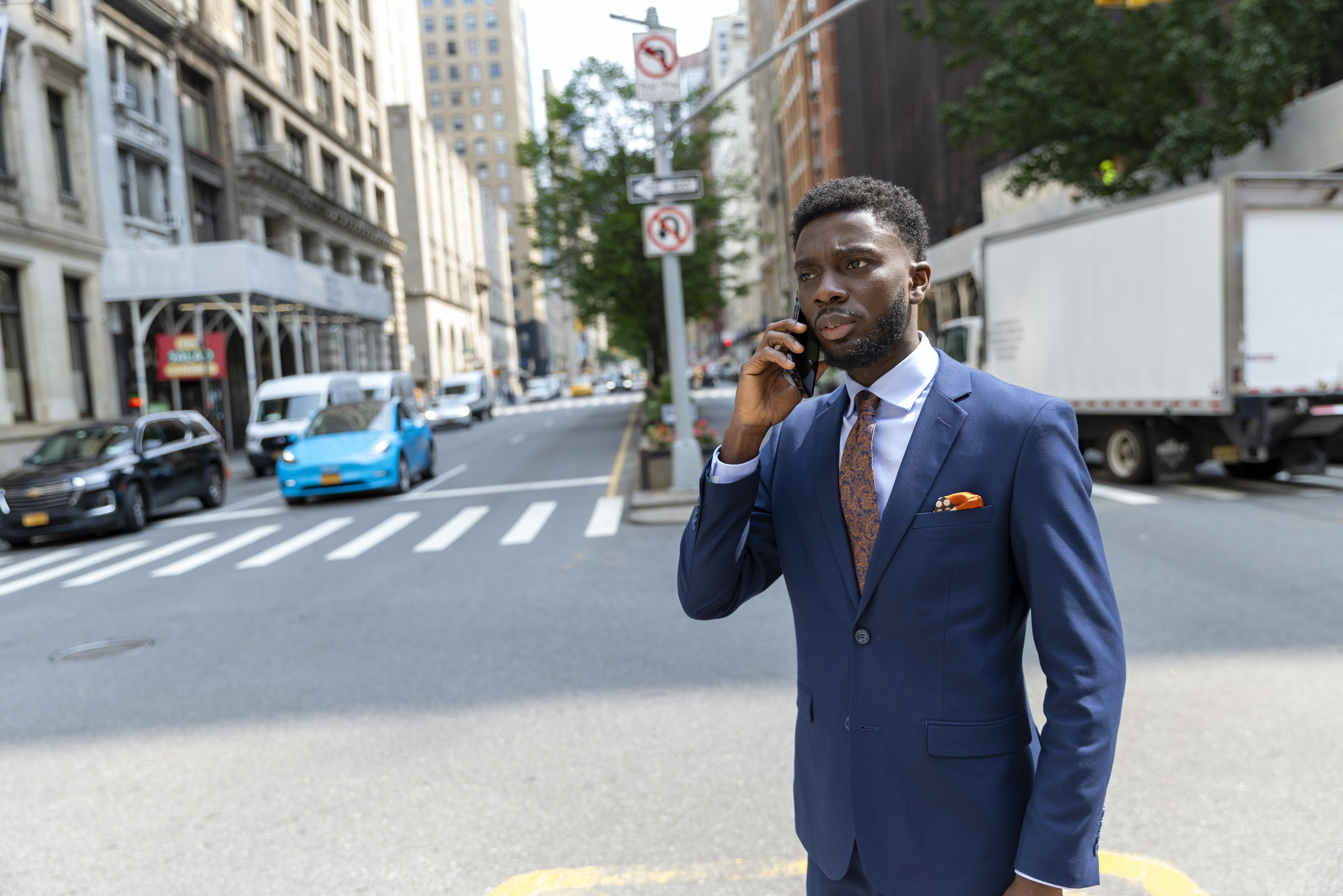 A man in a suit holding his phone at a street